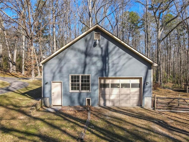 view of side of home with an outbuilding, fence, and driveway