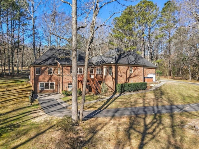 view of front facade featuring a front yard, brick siding, driveway, and stairs