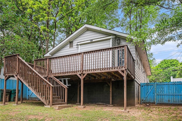 back of property with a gate, a wooden deck, stairway, and fence