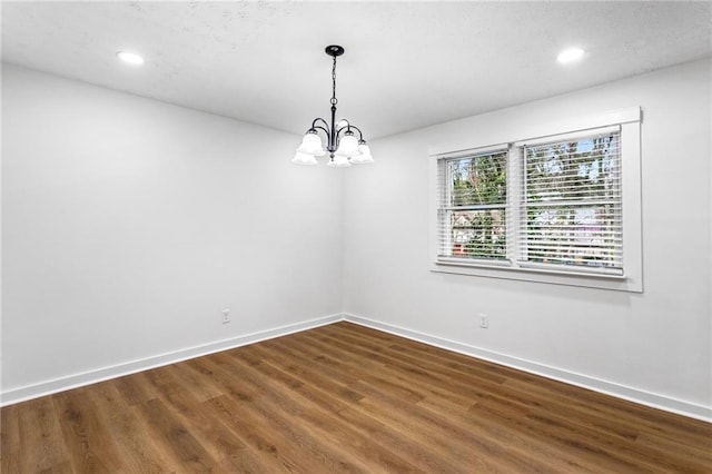 empty room with recessed lighting, baseboards, an inviting chandelier, and wood finished floors