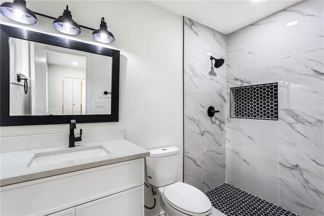 full bath with a marble finish shower, toilet, and vanity