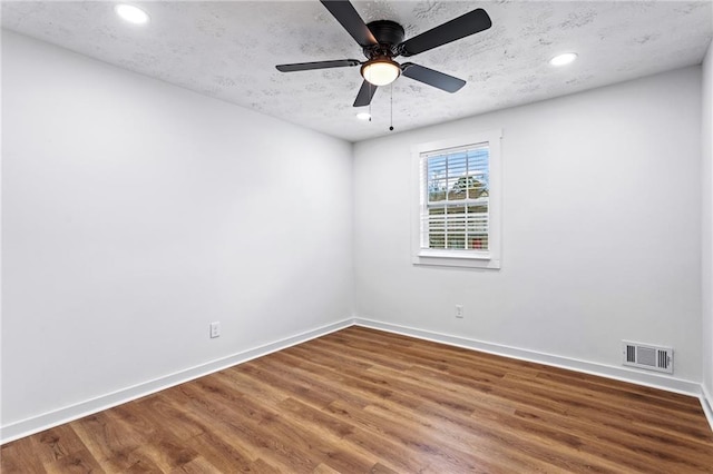 unfurnished room featuring a textured ceiling, wood finished floors, visible vents, and baseboards