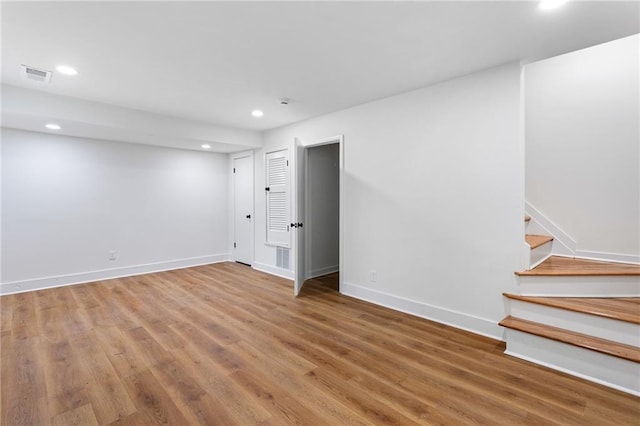 below grade area with visible vents, wood finished floors, recessed lighting, baseboards, and stairs