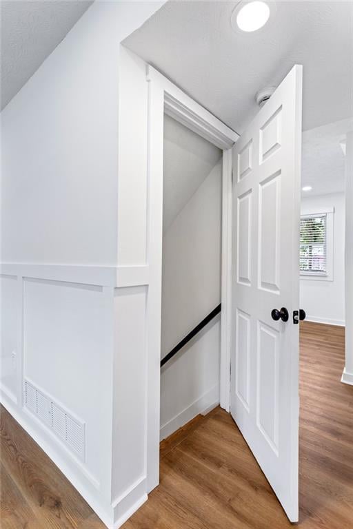 hall with visible vents, baseboards, and wood finished floors