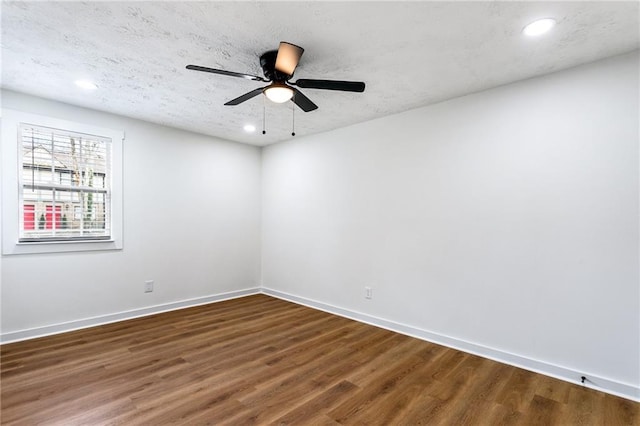 empty room with recessed lighting, baseboards, a textured ceiling, and wood finished floors