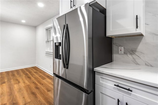 kitchen featuring white cabinets, wood finished floors, stainless steel refrigerator with ice dispenser, and backsplash