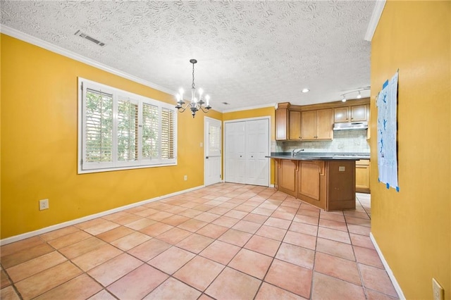 kitchen with ornamental molding, decorative light fixtures, a notable chandelier, and backsplash