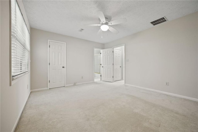 unfurnished bedroom featuring a textured ceiling, light carpet, and ceiling fan