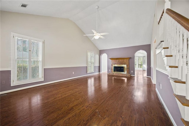 unfurnished living room with a brick fireplace, plenty of natural light, ceiling fan, and dark hardwood / wood-style floors