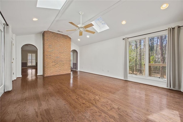 unfurnished living room featuring ceiling fan, dark wood-type flooring, and lofted ceiling with skylight