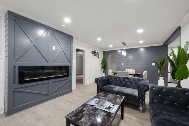 living room with light wood-type flooring and crown molding