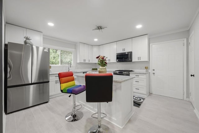 kitchen featuring light stone countertops, a center island, a breakfast bar area, white cabinets, and appliances with stainless steel finishes