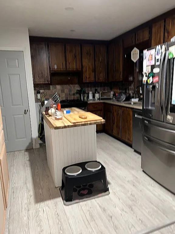 170 Beatrice St, Dallas, GA 30157 - kitchen with stainless steel fridge, dishwashing machine, dark brown cabinets, and a center island