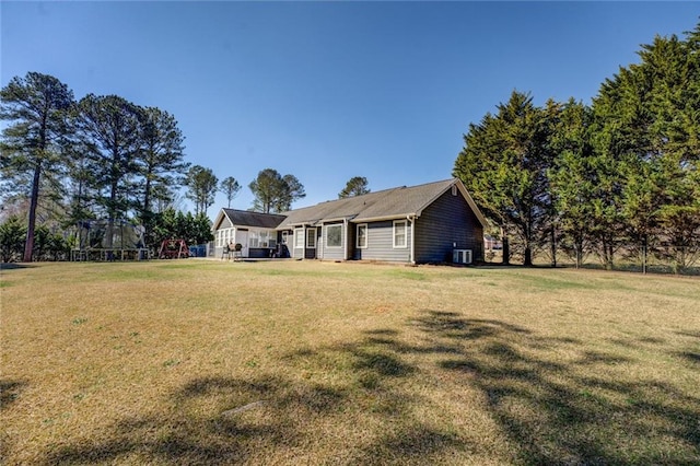 back of property featuring a playground and a lawn