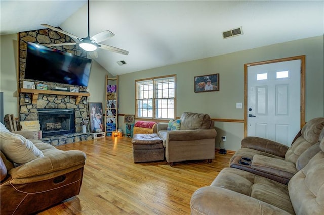 living room featuring lofted ceiling, a fireplace, visible vents, and wood finished floors