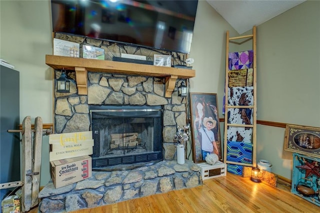 details featuring a stone fireplace and wood finished floors