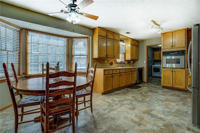 kitchen featuring stainless steel appliances, brown cabinetry, visible vents, and a sink