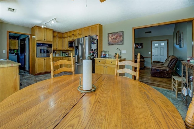 dining space with dark wood-style floors, rail lighting, and visible vents