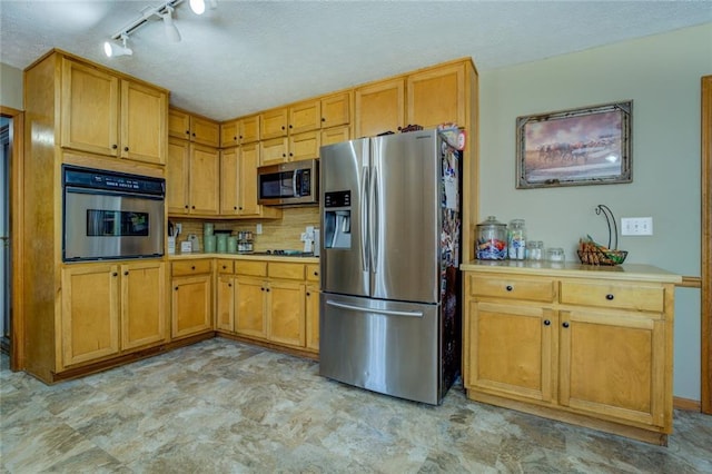 kitchen with a textured ceiling, light countertops, appliances with stainless steel finishes, and tasteful backsplash