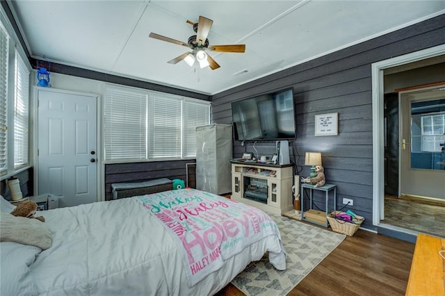 bedroom featuring a ceiling fan, multiple windows, visible vents, and wood finished floors