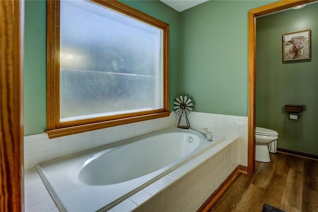 full bathroom featuring a bath, wood finished floors, toilet, and a healthy amount of sunlight