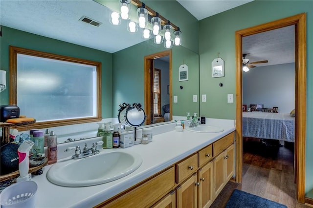 ensuite bathroom featuring wood finished floors, a sink, ensuite bath, and double vanity