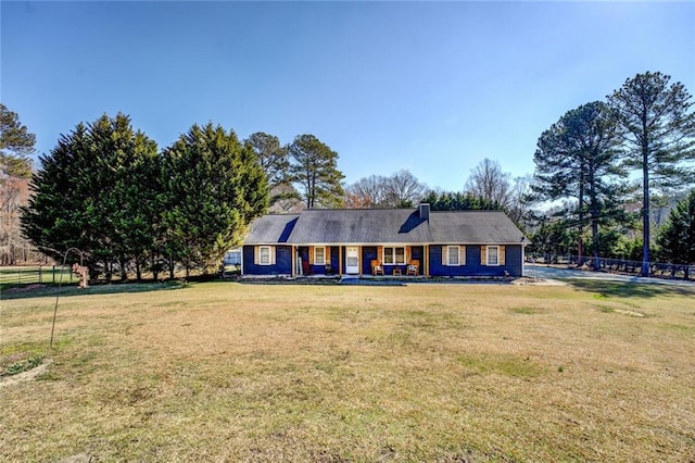 view of front of home featuring covered porch, a front lawn, and a chimney