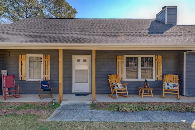 property entrance with covered porch and a shingled roof