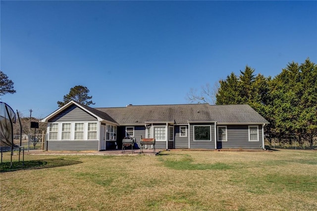 rear view of property with a patio, a trampoline, fence, and a lawn