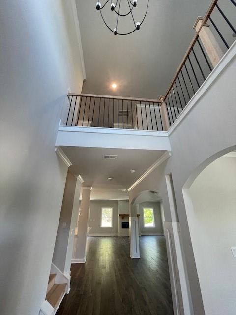 222 Silvercrest Dr, Acworth, GA 30101 - staircase with arched walkways, a towering ceiling, crown molding, wood finished floors, and a chandelier