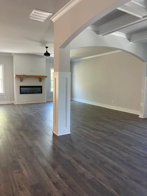 222 Silvercrest Dr, Acworth, GA 30101 - unfurnished living room featuring arched walkways, a ceiling fan, baseboards, dark wood-style flooring, and a glass covered fireplace