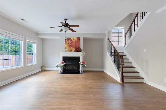 unfurnished living room featuring plenty of natural light, wood finished floors, and stairway