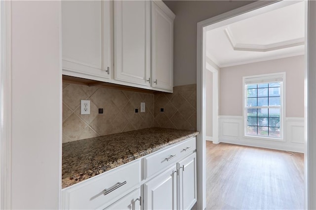 kitchen with wainscoting, stone countertops, light wood-style floors, white cabinets, and tasteful backsplash