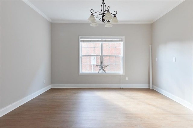 empty room with crown molding, baseboards, wood finished floors, and a chandelier