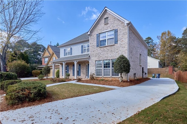 traditional-style house featuring fence, a front lawn, and brick siding