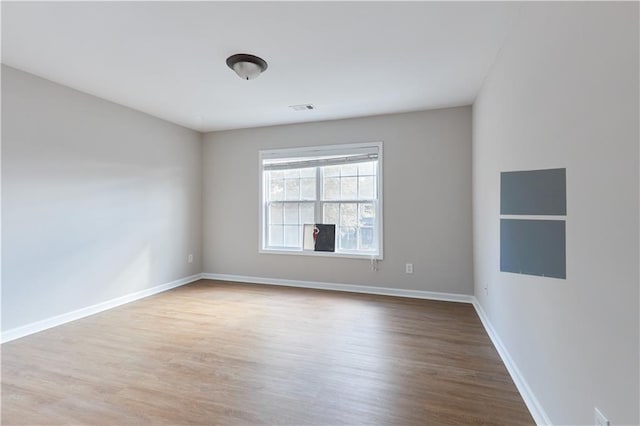 spare room with baseboards, visible vents, and wood finished floors