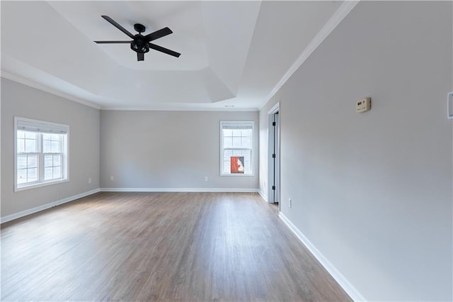 spare room with a healthy amount of sunlight, ceiling fan, a tray ceiling, and wood finished floors