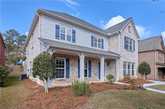 traditional-style home featuring central AC unit, a front lawn, and brick siding