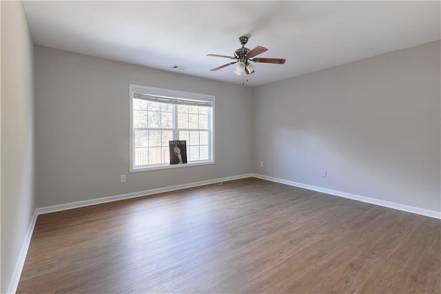 unfurnished room with a ceiling fan, dark wood-style floors, and visible vents