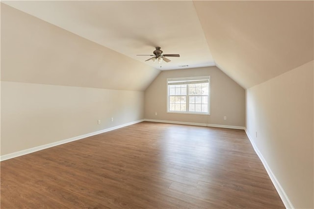 additional living space with baseboards, a ceiling fan, dark wood-style flooring, and lofted ceiling