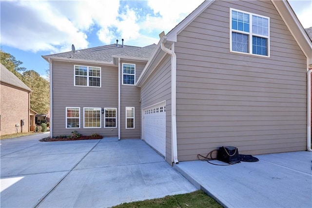rear view of house featuring concrete driveway