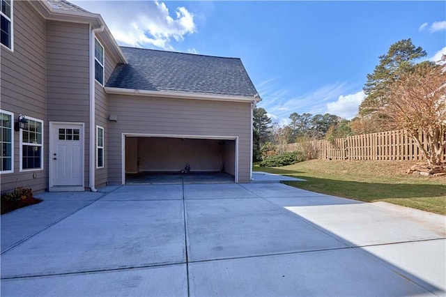 view of side of property featuring an attached garage, a shingled roof, fence, and driveway
