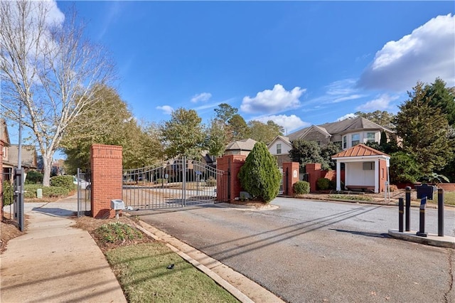 view of street featuring a gate, a gated entry, curbs, and sidewalks