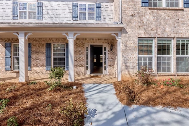 property entrance featuring covered porch and brick siding