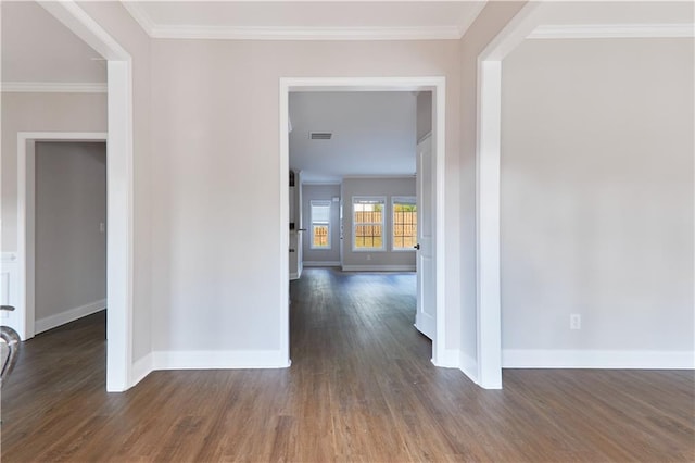 interior space with baseboards, ornamental molding, wood finished floors, and visible vents
