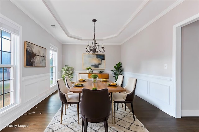 dining area with dark wood-style flooring, visible vents, a raised ceiling, a wainscoted wall, and a chandelier