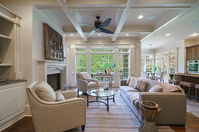 living room with ceiling fan, crown molding, coffered ceiling, dark wood-type flooring, and beam ceiling