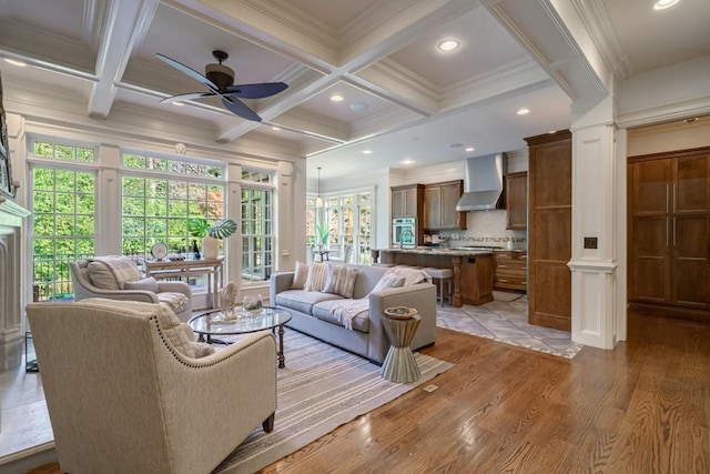 living room with beam ceiling, coffered ceiling, ceiling fan, and light wood-type flooring