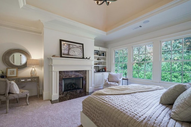 bedroom with a tray ceiling, crown molding, carpet flooring, and a fireplace