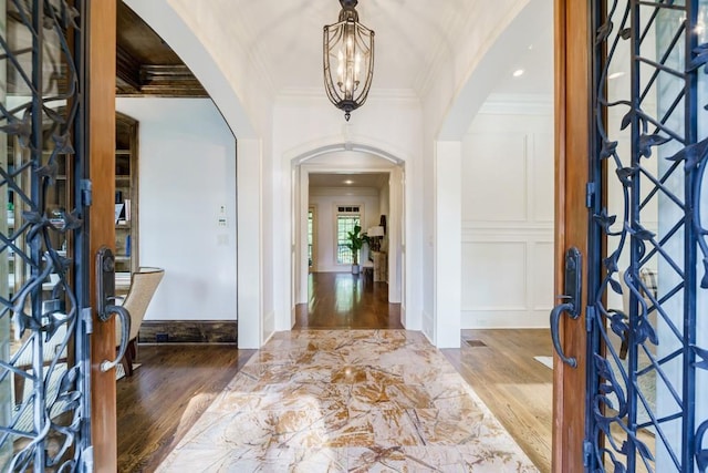 entrance foyer featuring a chandelier, ornamental molding, dark wood-type flooring, and french doors